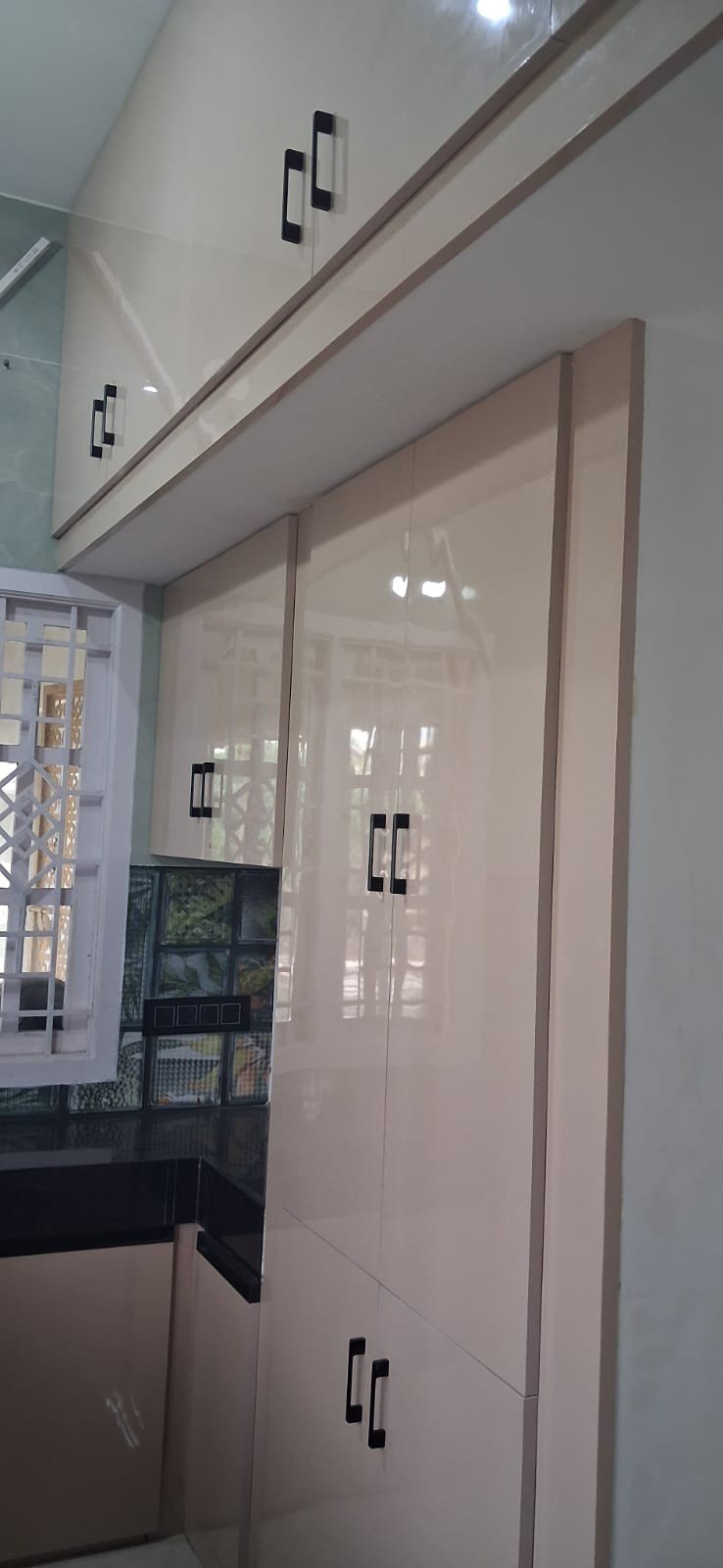 Glossy cream wardrobe and storage unit by Anjaneya Interiors